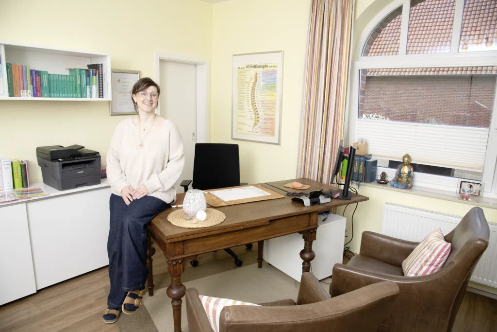 Kerstin Winner sitzt auf Ihrem Schreibtisch im Behandlungsraum