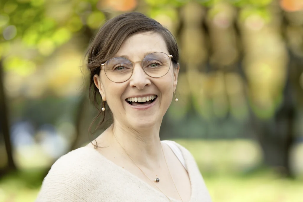 Kerstin Winner steht vor einem Waldhintergrund und strahlt in die Kamera