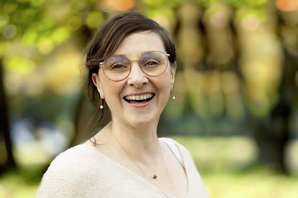 Kerstin Winner steht vor einem Waldhintergrund und strahlt in die Kamera